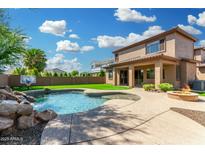 Resort-style backyard with a large pool, rock waterfall feature, covered patio and a built-in fire pit at 3099 E Claxton Ct, Gilbert, AZ 85297