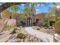 Stunning custom home with a stone tower, barrel tile roof, landscaped yard, and welcoming walkway to the arched entry door at 37334 N Winding Wash Trl, Carefree, AZ 85377