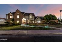 Charming two-story Tudor-style home featuring a brick facade and well-manicured lawn with accent lighting at 908 N Creston --, Mesa, AZ 85213
