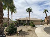 Charming single-story home featuring a well-maintained yard with desert landscaping and palm trees at 15471 W Post Cir, Surprise, AZ 85374