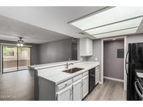 Bright kitchen featuring white cabinets, breakfast bar, updated countertops, and stainless steel sink at 2146 W Isabella Ave # 127, Mesa, AZ 85202