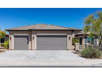 A spacious home featuring a three-car garage and a well-maintained front yard under a clear blue sky at 26168 W Tina Ln, Buckeye, AZ 85396