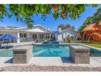 Stunning backyard featuring a refreshing pool, spa, outdoor kitchen, and fun playset at 4030 N 54Th Pl, Phoenix, AZ 85018