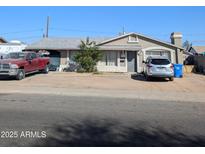 View of the home's front exterior featuring a driveway and partial landscaping and 2 vehicles at 4744 W Holly St, Phoenix, AZ 85035