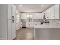 Bright kitchen boasts white cabinets, stainless steel appliances, marble backsplash, and quartz countertops at 119 E Hampton Ave, Mesa, AZ 85210