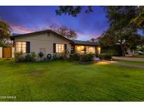 Charming single-story home featuring a well-manicured lawn and inviting landscaping, enhanced by subtle outdoor lighting at dusk at 141 E Bonita Way, Tempe, AZ 85281