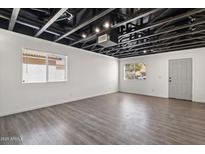Unfinished basement featuring exposed ceiling, laminate floors, white walls, and natural light from two windows at 1466 E Avenida Fresca --, Casa Grande, AZ 85122