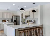 Bright kitchen boasts quartz countertops, stainless steel appliances, and bar seating at 1612 E Desert Rose Trl, San Tan Valley, AZ 85143