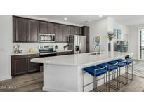 Modern kitchen features stainless appliances, dark cabinets, quartz counters, and stylish seating at the large island at 2511 W Queen Creek Rd # 262, Chandler, AZ 85248