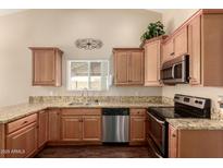 Well-lit kitchen featuring wooden cabinets, granite countertops, and stainless steel appliances at 2753 E Kenwood St, Mesa, AZ 85213