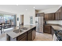 Bright kitchen with an island sink, stainless steel appliances, and an open layout leading to the dining area at 4646 E Maplewood St, Gilbert, AZ 85297