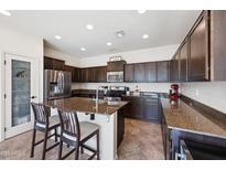 Beautiful kitchen with dark cabinetry, granite countertops, a large island with seating, and stainless steel appliances at 4646 E Maplewood St, Gilbert, AZ 85297