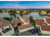 Stunning aerial view of waterfront homes with tile roofs, lush landscaping, and access to a serene lake community at 1700 E Lakeside Dr # 12, Gilbert, AZ 85234