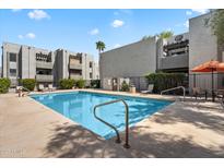 Community pool with lounge chairs and umbrella seating for residents on a sunny day at 8020 E Thomas Rd # 215, Scottsdale, AZ 85251