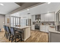 Bright kitchen boasts white cabinets, stainless steel appliances, island with seating, and wood-look tile flooring at 8726 E Devonshire Ave Ave, Scottsdale, AZ 85251