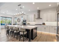 Stylish kitchen featuring a large island, white cabinets, stainless steel appliances, and pendant lighting at 5931 E Sierra Morena St, Mesa, AZ 85215