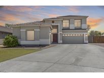 Two-story home with a large driveway, desert landscaping, and a welcoming red front door at 11259 W Locust Ln, Avondale, AZ 85323
