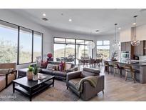 Bright, open-concept living room features large windows and access to an outdoor patio with dining and lounge furniture at 15332 E Hidden Springs Trl, Fountain Hills, AZ 85268