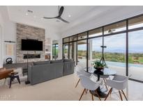 Contemporary living room with a stone fireplace, comfortable seating, and sliding glass doors leading to the outdoors at 15332 E Hidden Springs Trl, Fountain Hills, AZ 85268