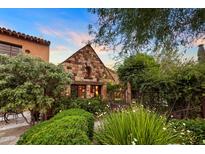 Charming stone cottage-style home with lush landscaping and a welcoming, idyllic facade at sunset at 27050 N 103Rd St, Scottsdale, AZ 85262