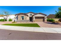 Charming single-story home featuring stone accents, a two-car garage, and a well-manicured lawn at 30857 N 128Th Dr, Peoria, AZ 85383