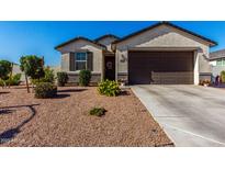 Charming single story home with a brown two car garage and colorful desert landscaping at 36204 W San Sisto Ave, Maricopa, AZ 85138