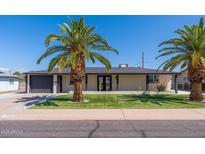 Charming single-story home featuring mature palm trees, freshly cut grass, and a dark gray attached garage at 5452 E University Dr, Mesa, AZ 85205