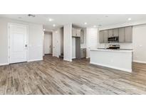 Bright open-concept living space with wood-look tile flooring and a view of the kitchen at 5828 E Covey Ln, Phoenix, AZ 85054