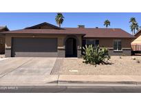 Charming single-story home featuring desert landscaping, a two-car garage, and a welcoming arched entryway at 2130 W Devonshire St, Mesa, AZ 85201