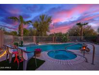 A backyard pool and hot tub features lush landscaping and a beautiful dusk sky at 6853 S Russet Sky Way, Gold Canyon, AZ 85118