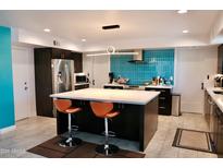 Modern kitchen featuring a large island, stainless steel appliances, and blue glass tile backsplash at 11035 N 37Th St, Phoenix, AZ 85028
