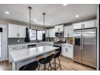Bright kitchen with stainless steel appliances, white cabinets, stone countertops and pendant lighting at 18642 N 13Th Ave, Phoenix, AZ 85027