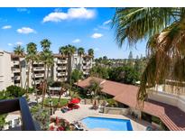 Community pool with lounge chairs, palm trees, and a building with red tile roof at 4200 N Miller Rd # 503, Scottsdale, AZ 85251