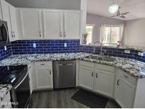 Modern kitchen featuring stainless steel appliances, granite countertops, and a blue tile backsplash at 11760 N 153Rd Ave, Surprise, AZ 85379