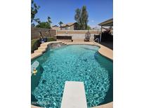 Backyard pool featuring a diving board, rock waterfall, brick surround, and desert landscaping at 11760 N 153Rd Ave, Surprise, AZ 85379