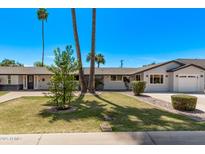 Charming single-story home featuring a well-manicured lawn, mature palm trees and a cozy, inviting facade at 1431 E San Juan Ave, Phoenix, AZ 85014