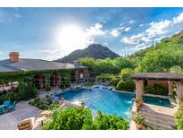 An exquisite backyard pool area features a spa, lush landscaping, and mountain views at 16469 N 113Th Way, Scottsdale, AZ 85255