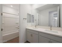Bright bathroom features double sinks, a large mirror, and a shower-tub combination at 17319 W Via Dona Rd, Surprise, AZ 85387