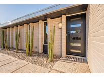 Modern entryway featuring a sleek black door, desert landscaping, and a stylish exterior lighting at 20 W Canterbury Ln, Phoenix, AZ 85023