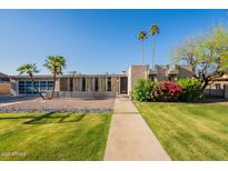 Stunning contemporary home featuring a lush green lawn, desert landscaping, and a striking modern design at 20 W Canterbury Ln, Phoenix, AZ 85023