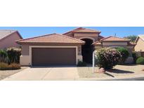 Charming single-story home featuring a terracotta roof, brown garage door, and desert landscaping at 3928 N 151St Ave, Goodyear, AZ 85395
