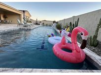 Inviting pool featuring colorful floaties, lounge chairs, patio seating, and water feature, perfect for outdoor relaxation at 11934 S 181St Ave, Goodyear, AZ 85338