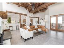 Spacious living room featuring high ceilings, exposed beams, tile flooring, and views into the kitchen area at 13554 E Columbine Dr, Scottsdale, AZ 85259