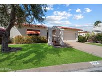 A charming home features lush green grass, mature trees, and a covered entrance with a red tile roof at 7644 E Sandalwood Dr, Scottsdale, AZ 85250