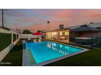 Backyard pool with lighting feature at dusk, surrounded by green turf, a hot tub, and lounge furniture at 8522 E Virginia Ave, Scottsdale, AZ 85257