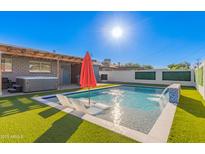 Stunning pool featuring a modern water feature, in-water lounge chairs and vibrant artificial turf at 8522 E Virginia Ave, Scottsdale, AZ 85257