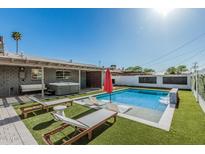 Outdoor space with a pool, water feature, lounge chairs, artificial turf, and a covered sitting area at 8522 E Virginia Ave, Scottsdale, AZ 85257