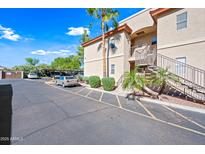 Condo exterior featuring tan stucco, desert landscaping, parking, and entry stairs at 10410 N Cave Creek Rd # 1100, Phoenix, AZ 85020