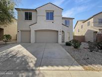 Two-story home featuring a three-car garage, neutral stucco, and desert landscaping in front at 30271 W Crittenden Ln, Buckeye, AZ 85396