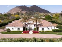 Stunning white home featuring a beautiful tile roof, palm trees, and vibrant landscaping against a mountain backdrop at 5220 N Casa Blanca Dr, Paradise Valley, AZ 85253
